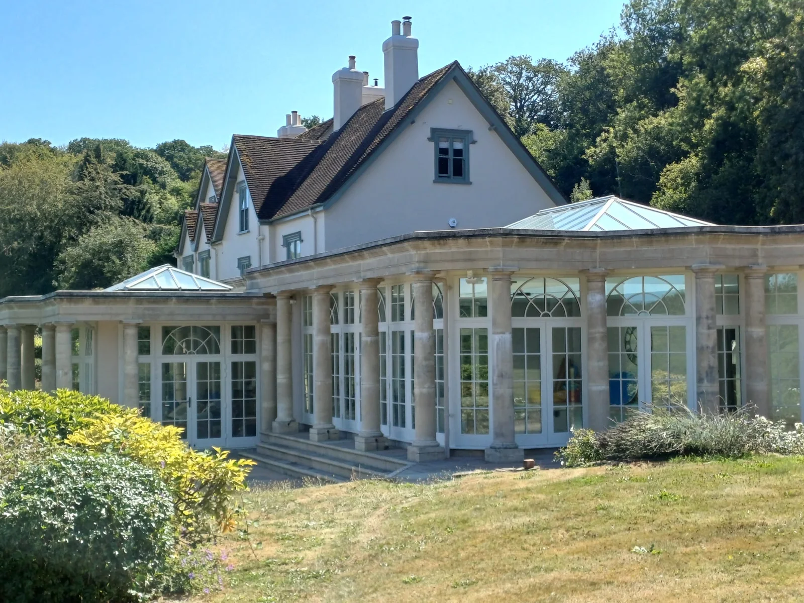 Country house with a stone colonnaded orangery, exterior painted and maintained by Bourne Decorators